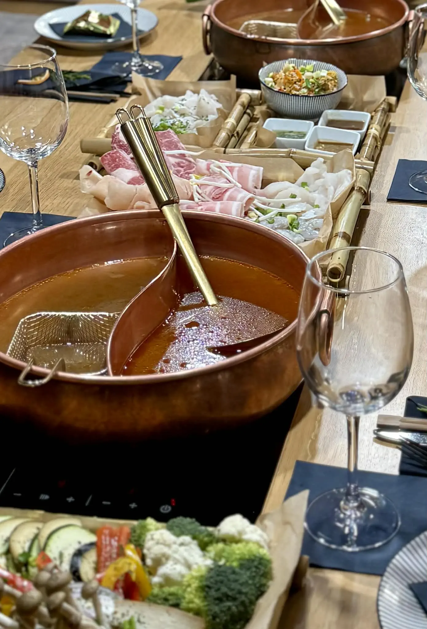 Stół hot pot z dodatkami – mięso, warzywa, sosy.